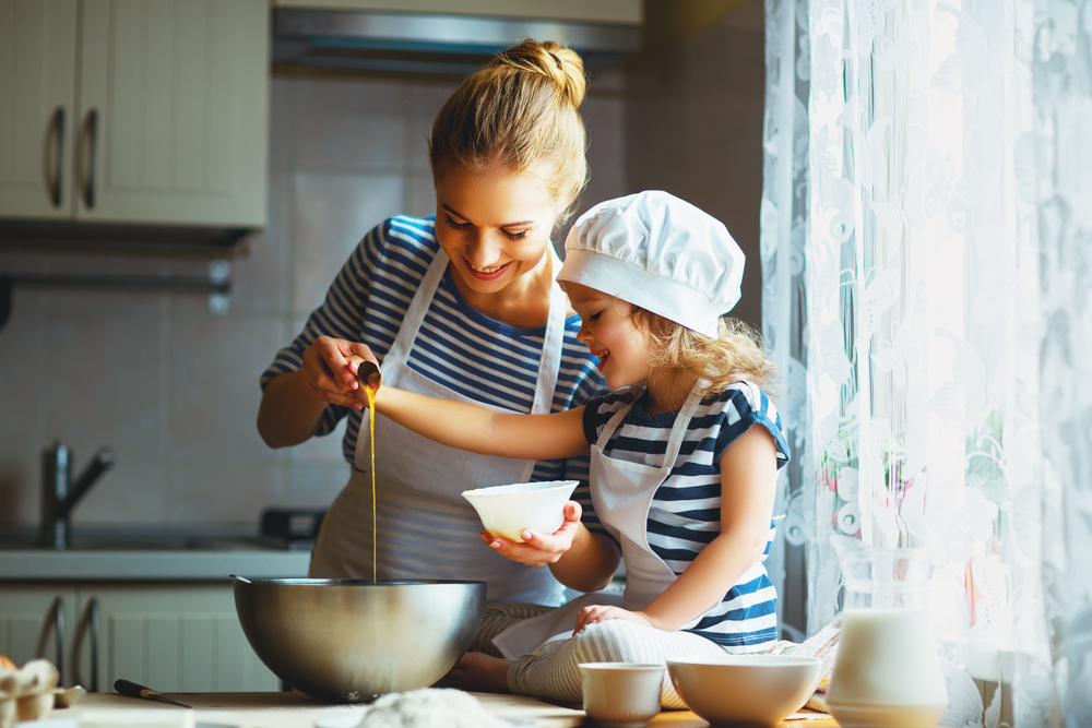 little girl is cooking with her mother in the kitchen